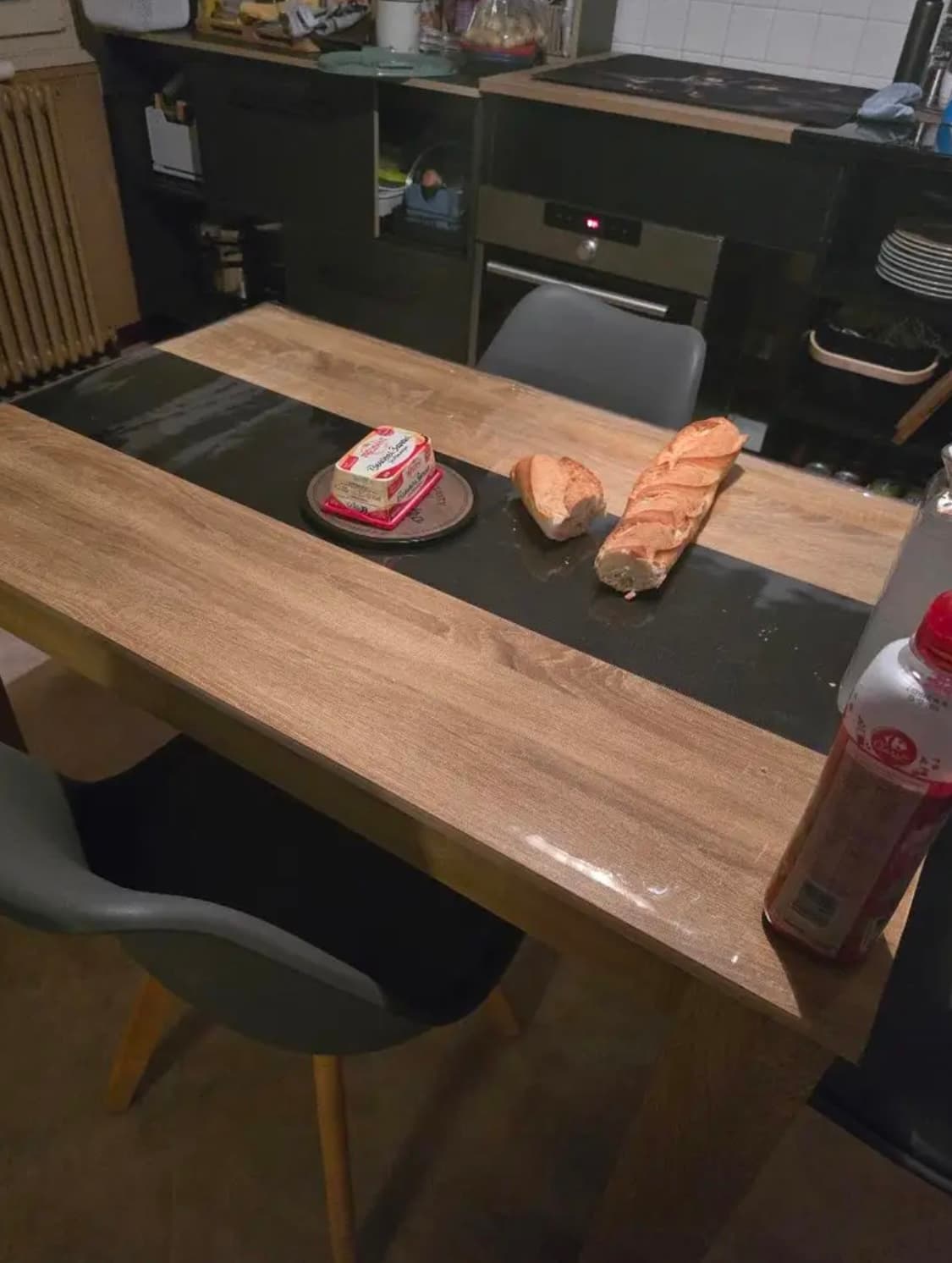 Mesa de cocina con banda oscura en el centro: baguette y mantequilla apoyada en vidrio suave