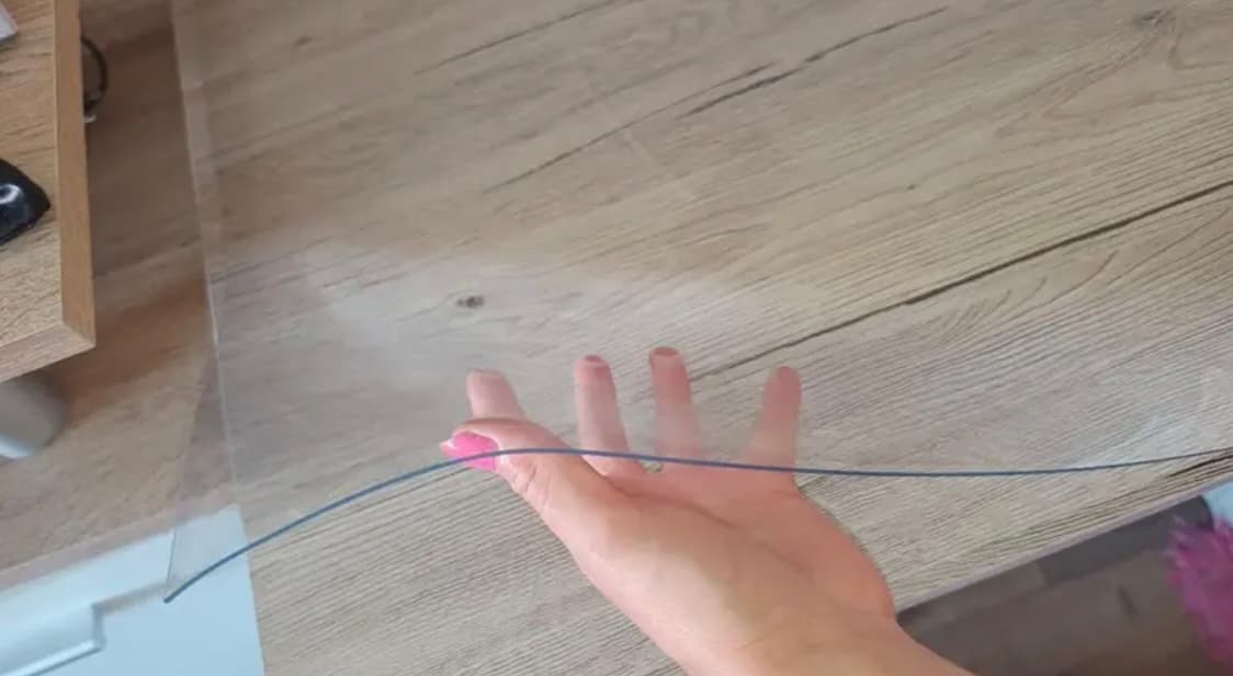Una mano strung debajo de la alfombra transparente acostada en una parte superior de madera ligera