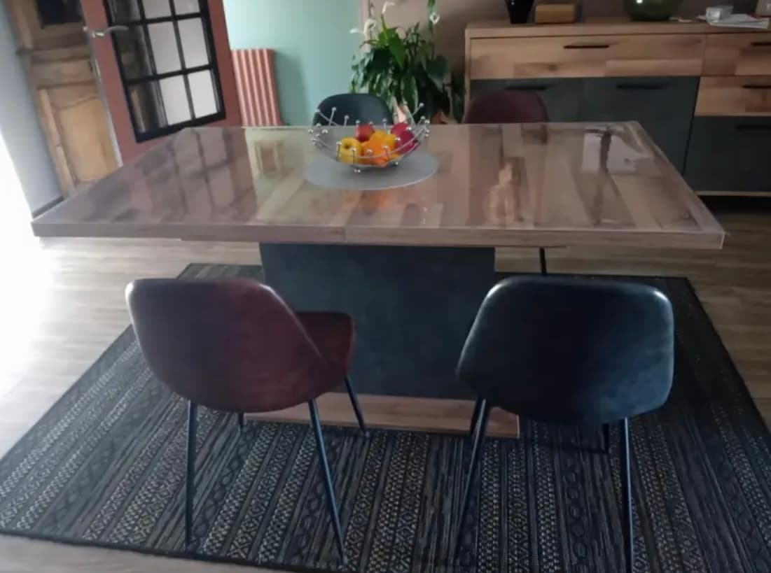 Mesa ampliable en madera nudosa con cesta de frutas; dos sillas de cuero en la alfombra
