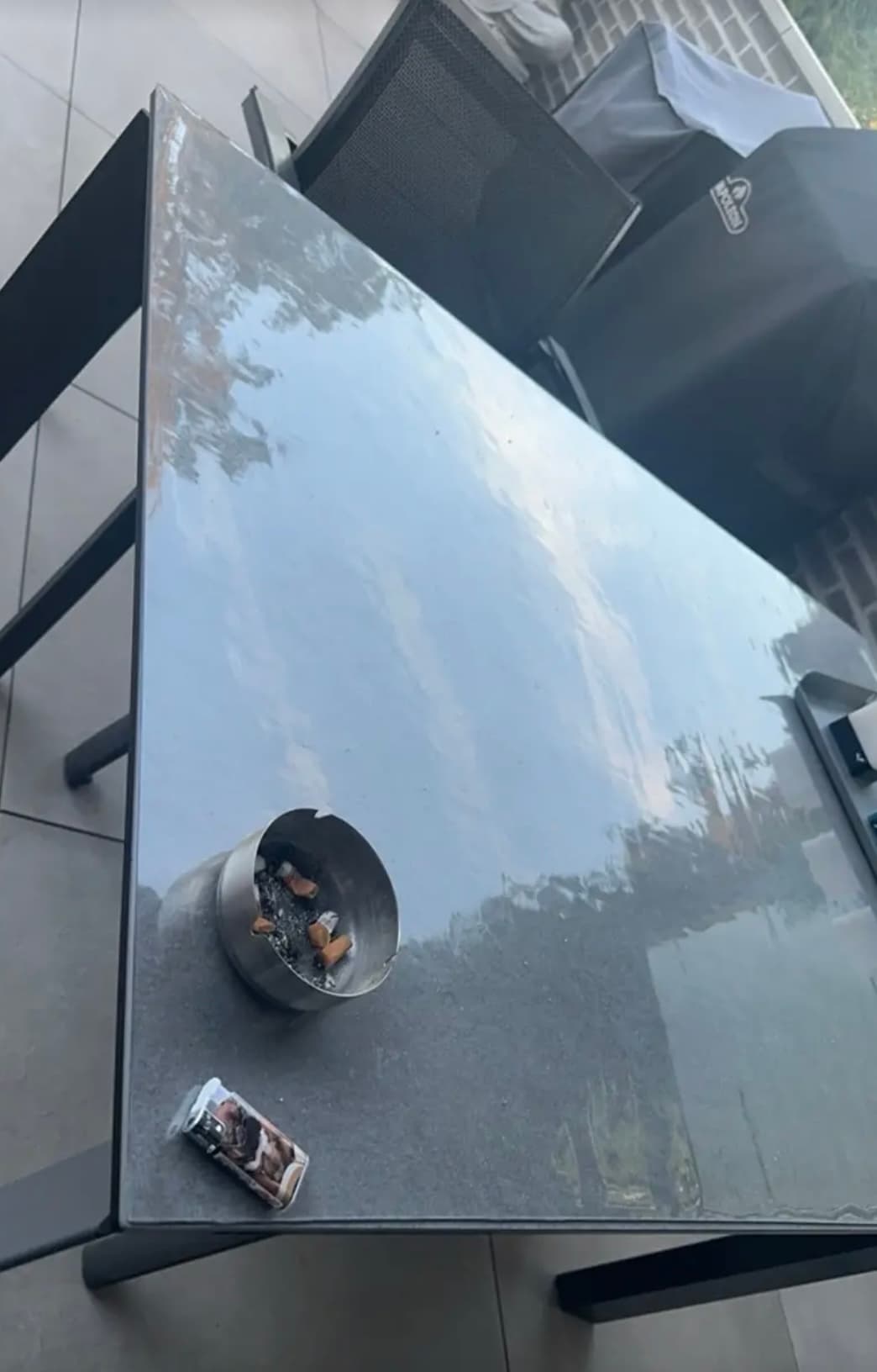 Mesa en la terraza desde arriba: en la estera se refleja el cielo de la noche, junto a un cenicero