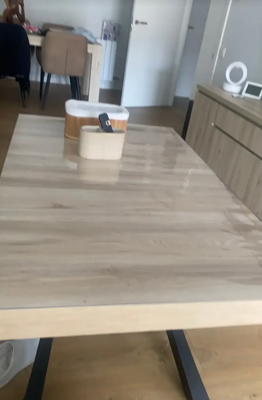 Mesa de luz en salón con soporte de madera; la estera refleja la luz de la ventana