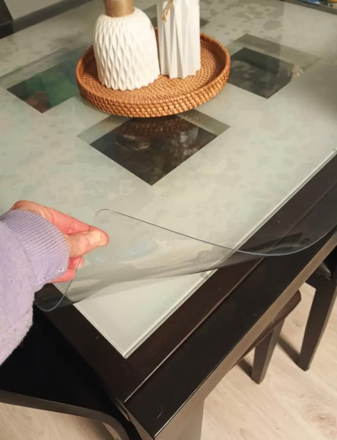 Una mano sacudida la estera de la mesa oscura con la tapa de cristal satinado y la bandeja de rattan