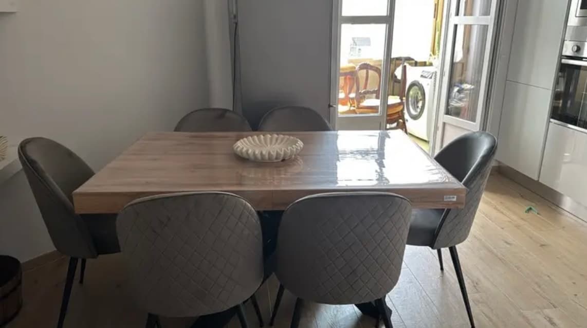 Mesa de cocina con seis sillas grises: en la alfombra recién colocada queda la etiqueta
