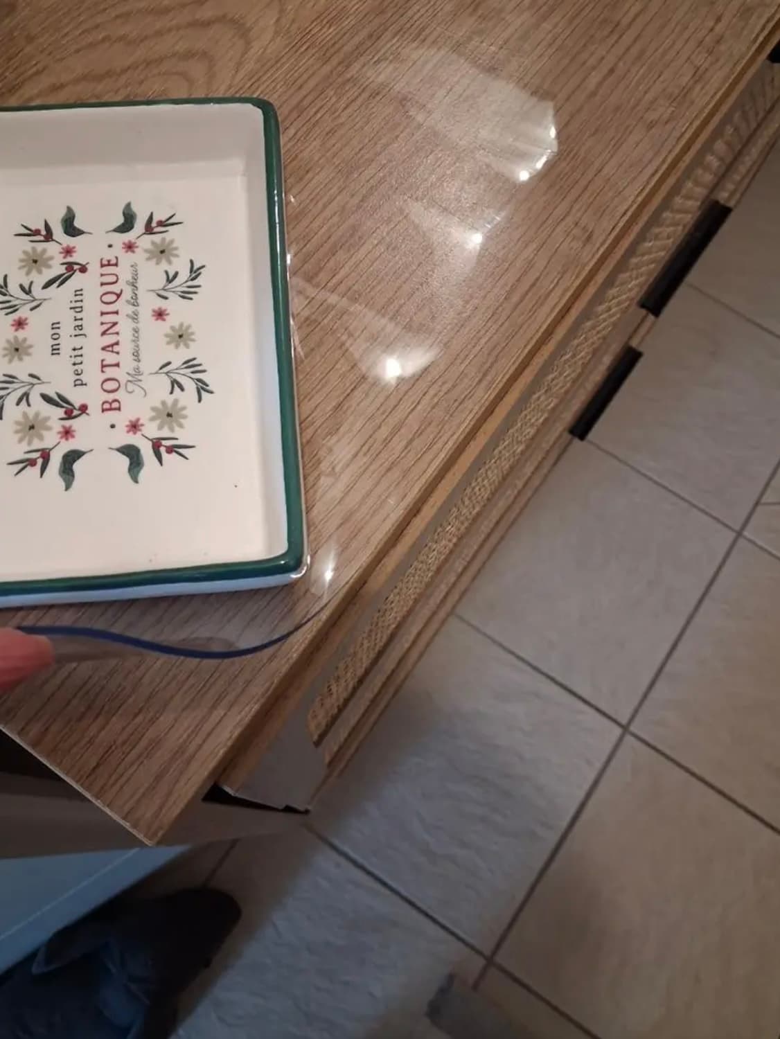 Corner de un aparador de roble con bandeja decorada; una mano sostiene el borde de la película